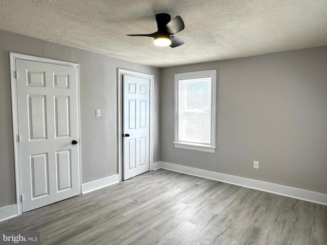 unfurnished bedroom featuring baseboards, ceiling fan, wood finished floors, a textured ceiling, and a closet