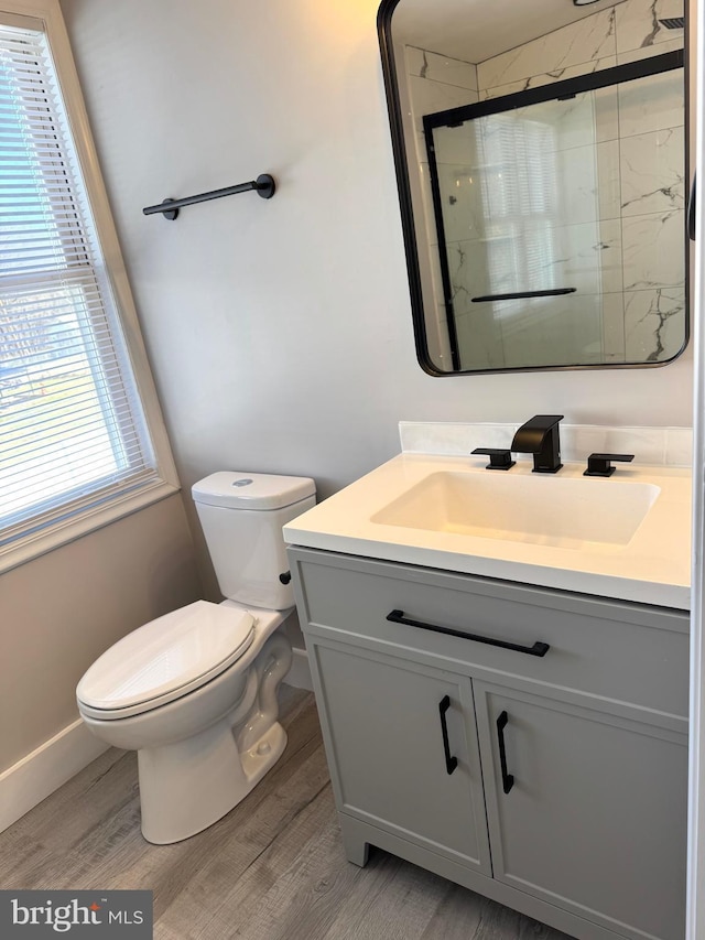 full bathroom featuring vanity, wood finished floors, toilet, and a shower stall