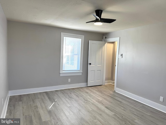 unfurnished bedroom with a textured ceiling, wood finished floors, a ceiling fan, and baseboards