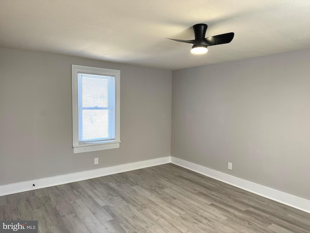 spare room featuring wood finished floors, a ceiling fan, and baseboards