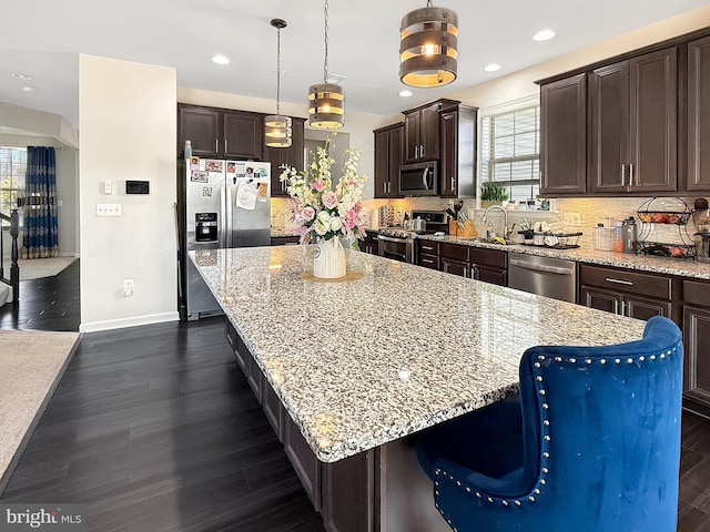 kitchen featuring decorative backsplash, a large island, dark wood-type flooring, dark brown cabinetry, and appliances with stainless steel finishes