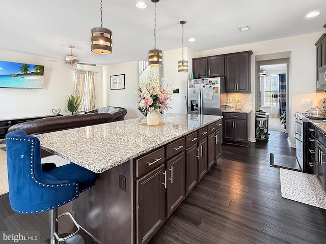 kitchen with visible vents, light stone counters, tasteful backsplash, appliances with stainless steel finishes, and dark wood-style flooring