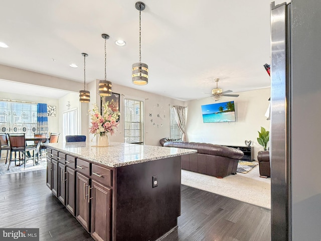 kitchen featuring hanging light fixtures, open floor plan, dark brown cabinets, and dark wood-style flooring