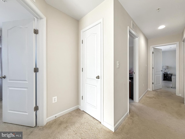 hallway with baseboards, light carpet, and visible vents