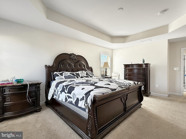 bedroom featuring a raised ceiling, light colored carpet, visible vents, and baseboards