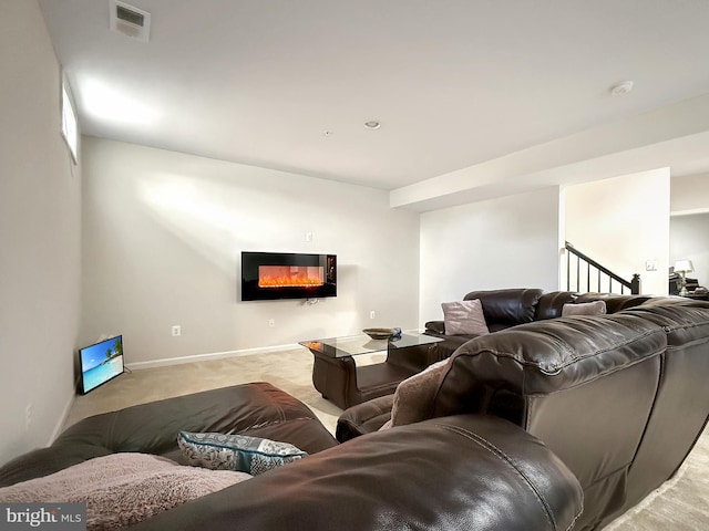 living area with visible vents, baseboards, stairs, light carpet, and a glass covered fireplace