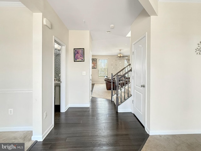 hallway featuring baseboards, dark wood-type flooring, and stairs