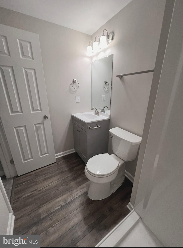 bathroom with baseboards, toilet, wood finished floors, and vanity