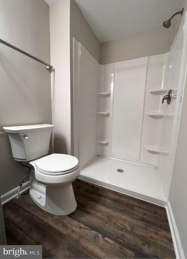 bathroom with baseboards, toilet, walk in shower, and wood finished floors