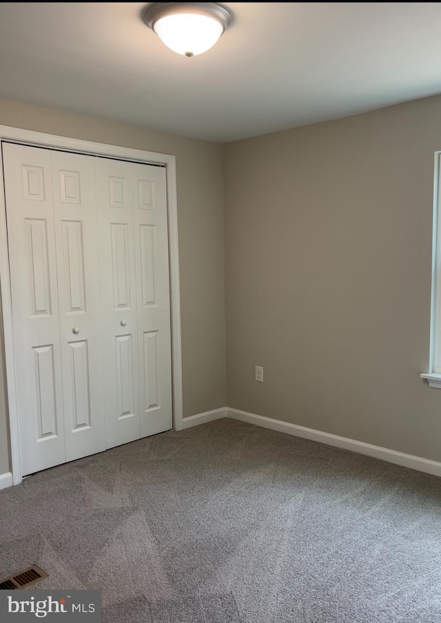 unfurnished bedroom featuring visible vents, carpet, a closet, and baseboards