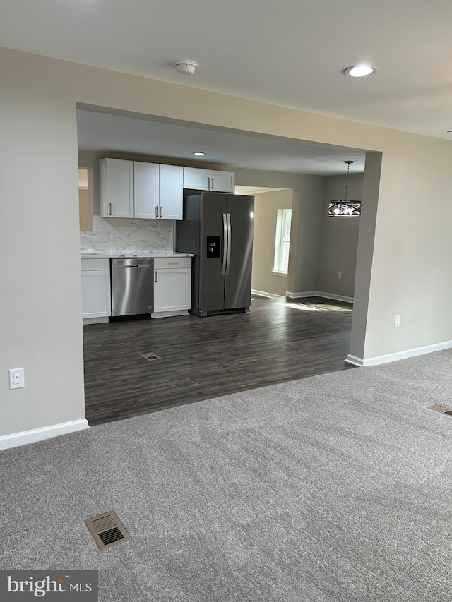 kitchen featuring visible vents, backsplash, appliances with stainless steel finishes, white cabinets, and dark colored carpet