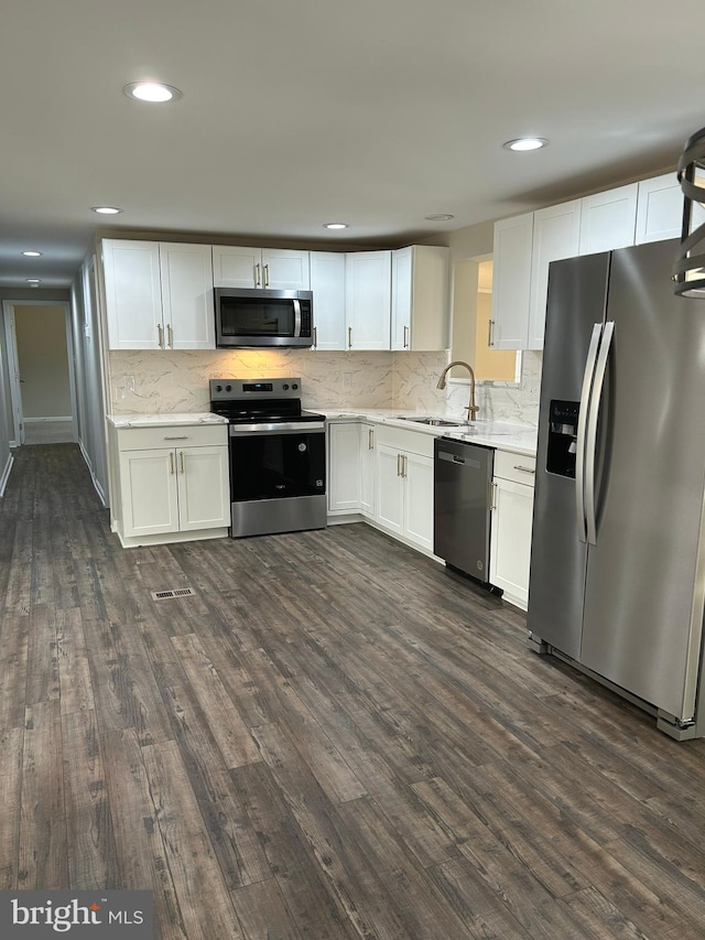 kitchen with dark wood finished floors, appliances with stainless steel finishes, white cabinetry, and a sink