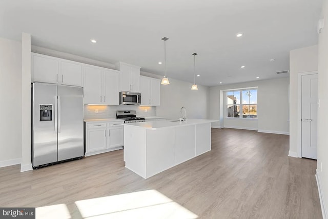 kitchen with light countertops, decorative backsplash, appliances with stainless steel finishes, white cabinets, and a sink