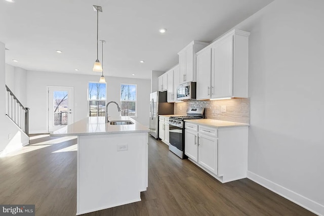 kitchen with backsplash, dark wood finished floors, an island with sink, appliances with stainless steel finishes, and white cabinets