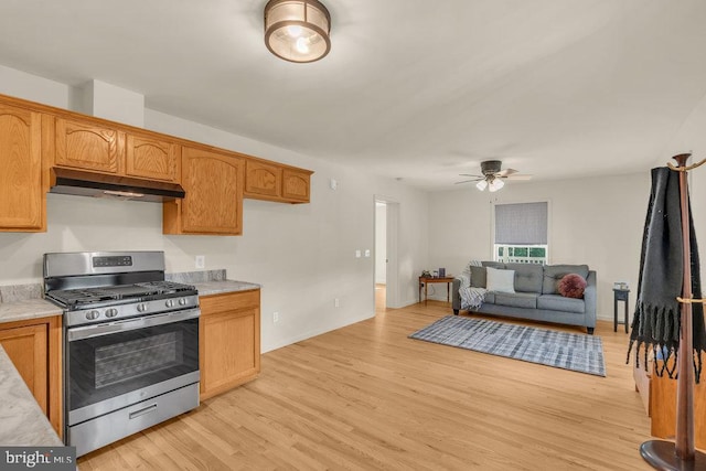 kitchen with light countertops, light wood-style floors, stainless steel gas range, and under cabinet range hood