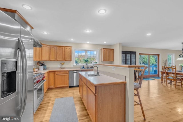 kitchen featuring stainless steel appliances, light wood-type flooring, a kitchen bar, and a sink