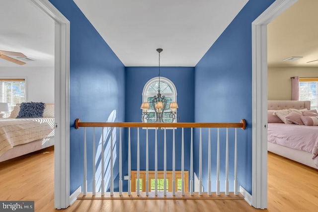 hall with wood finished floors and a notable chandelier