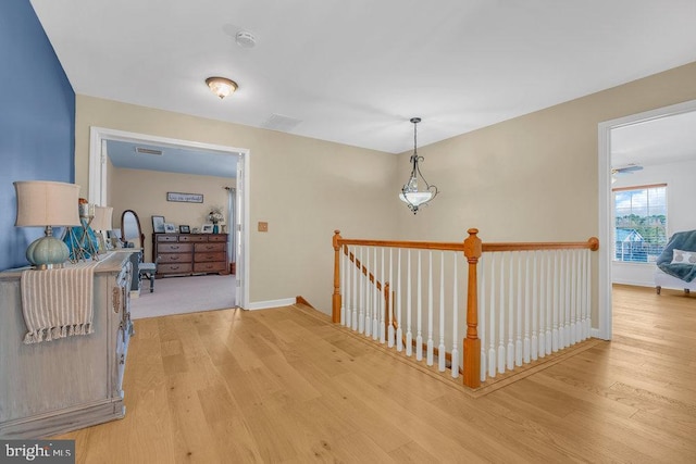 hall featuring baseboards, an upstairs landing, and wood finished floors