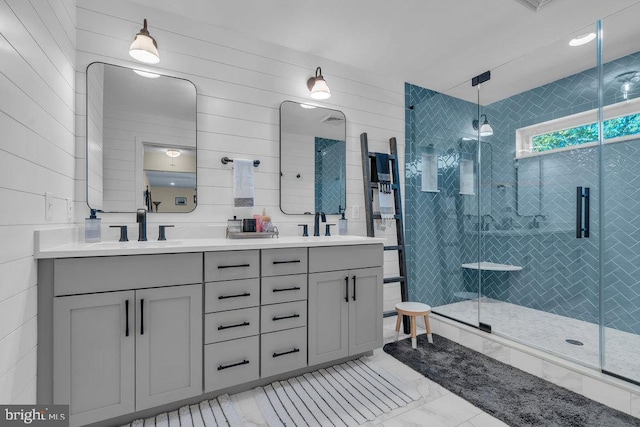 bathroom with a sink, tile walls, marble finish floor, double vanity, and a stall shower