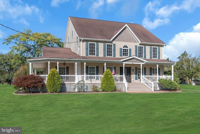 colonial inspired home with roof with shingles, a porch, and a front yard