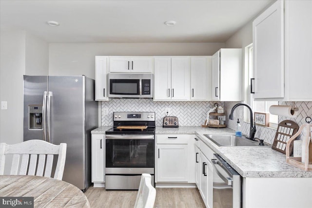 kitchen featuring light countertops, appliances with stainless steel finishes, a sink, and white cabinetry