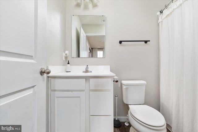 bathroom featuring toilet, baseboards, and vanity