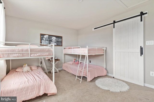 carpeted bedroom with a barn door and baseboards