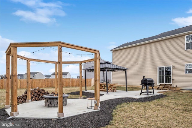 view of yard with entry steps, a fire pit, fence, a gazebo, and a patio area