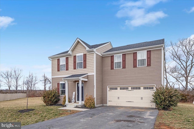 traditional-style home featuring a garage, aphalt driveway, and a front yard