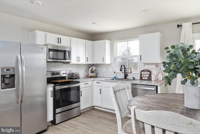 kitchen with appliances with stainless steel finishes, a sink, and white cabinetry