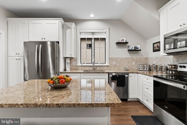 kitchen with dark wood finished floors, tasteful backsplash, appliances with stainless steel finishes, white cabinets, and a sink