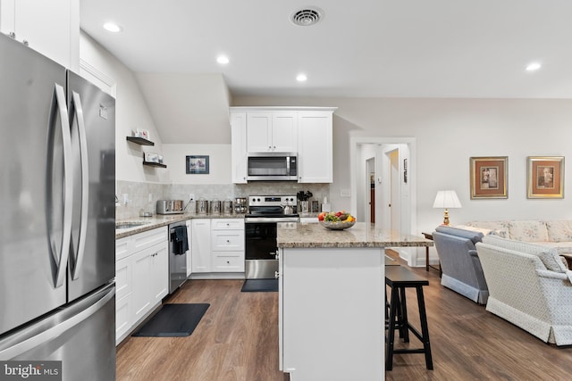 kitchen featuring a breakfast bar, dark wood-style flooring, visible vents, open floor plan, and appliances with stainless steel finishes