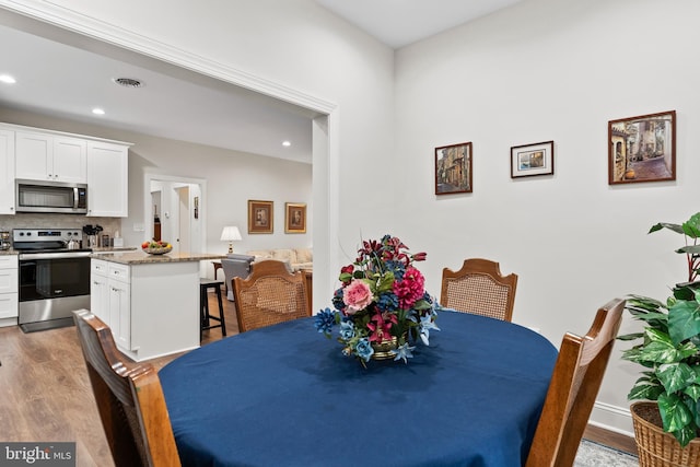 dining room featuring wood finished floors, visible vents, and recessed lighting