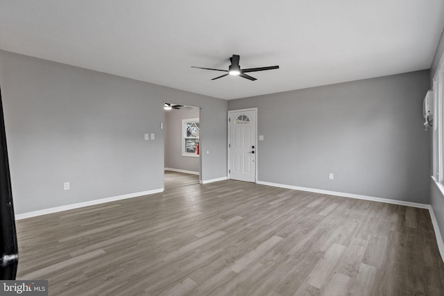 unfurnished living room with wood finished floors, a ceiling fan, and baseboards