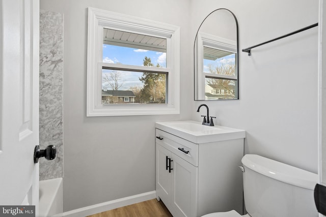 bathroom featuring toilet, baseboards, wood finished floors, and vanity