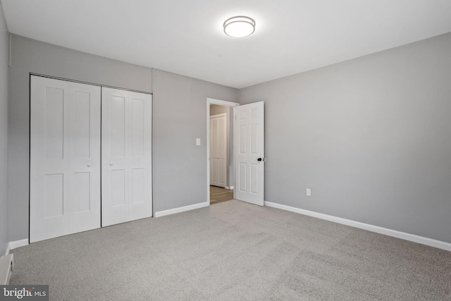 unfurnished bedroom with carpet floors, a closet, and baseboards