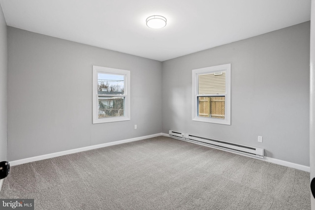 carpeted spare room featuring a baseboard heating unit and baseboards