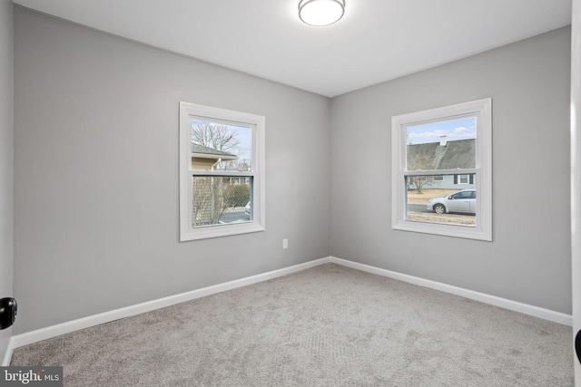 carpeted empty room featuring baseboards