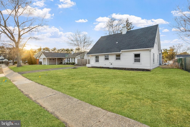 back of property featuring roof with shingles, a chimney, fence, and a yard