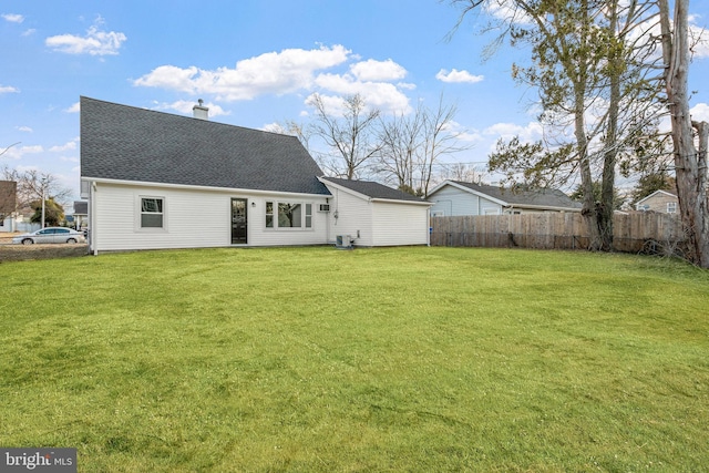 rear view of property with a shingled roof, a lawn, a chimney, fence, and central AC