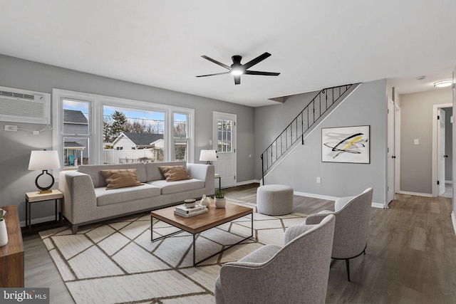 living area with baseboards, stairway, wood finished floors, and a wall mounted AC