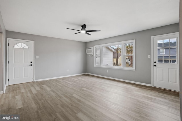 entrance foyer featuring light wood-style floors, a ceiling fan, baseboards, and an AC wall unit