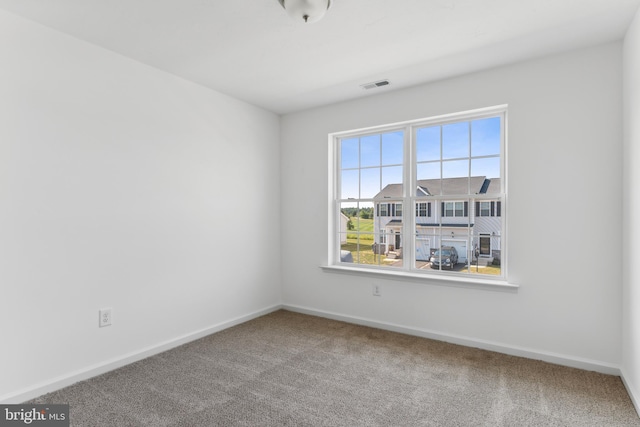 carpeted spare room with visible vents and baseboards