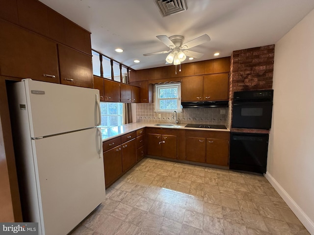 kitchen with visible vents, black appliances, a sink, under cabinet range hood, and tasteful backsplash