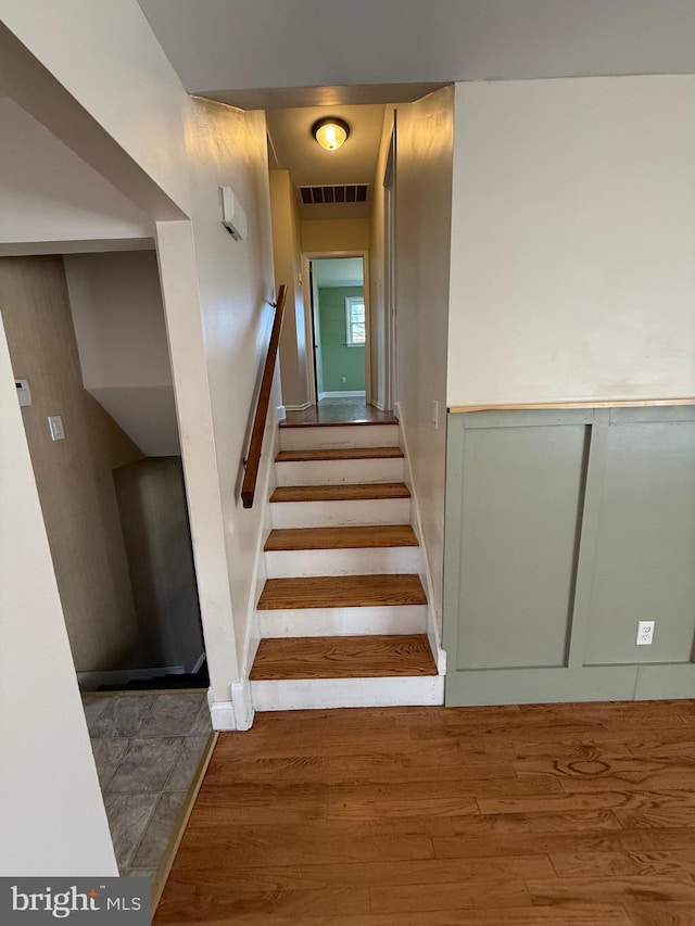 staircase featuring wood finished floors and visible vents