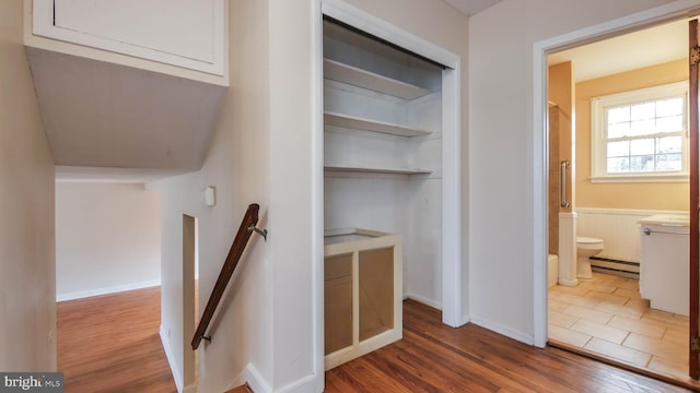 interior space with an upstairs landing, baseboard heating, and wood finished floors