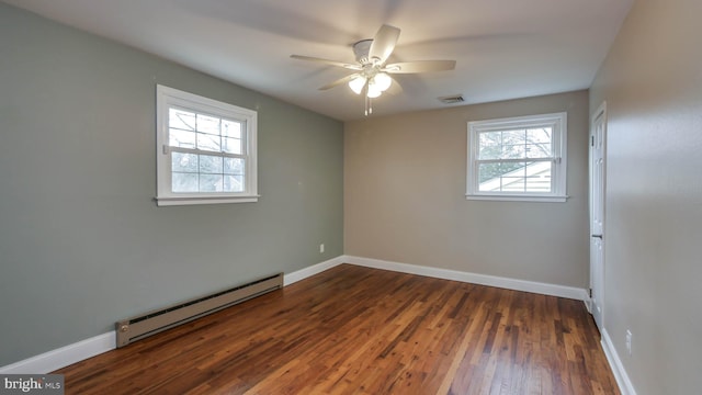 spare room with a ceiling fan, wood finished floors, baseboards, visible vents, and baseboard heating