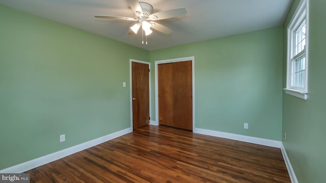 unfurnished bedroom featuring a closet, baseboards, and dark wood-style flooring