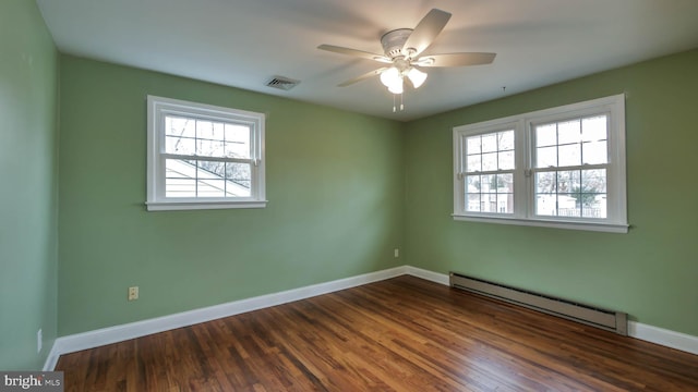 empty room featuring visible vents, baseboards, baseboard heating, and dark wood finished floors