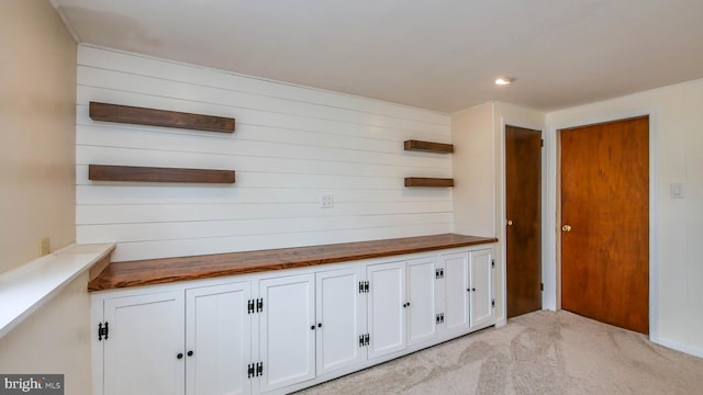 interior space with open shelves, light carpet, white cabinets, and wooden counters